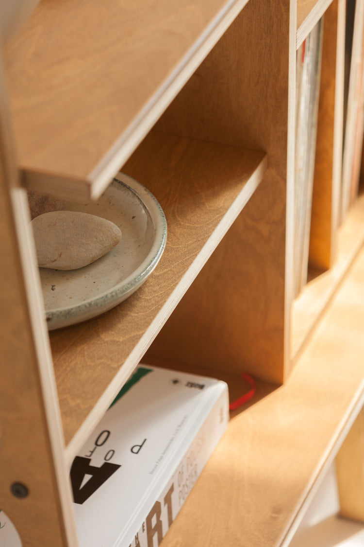 Stack of ceramic plates on a wooden shelf with a blurred background