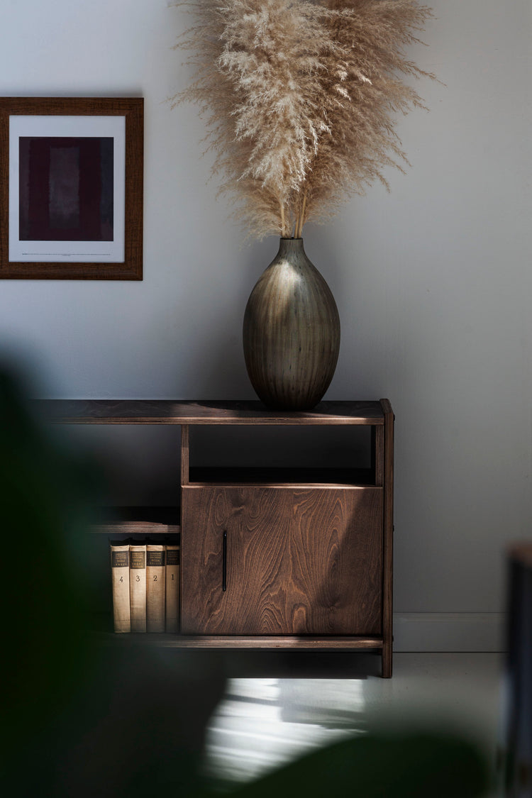 Wooden cabinet with a vase and pampas grass against a gray wall