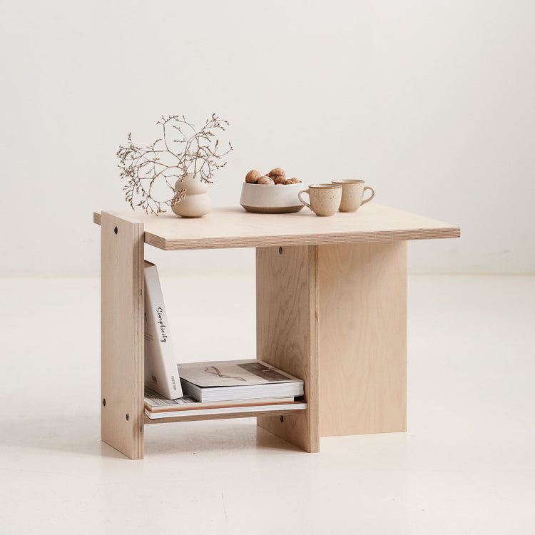 Wooden side table with a shelf, featuring a plant, bowls, and cups on a light background