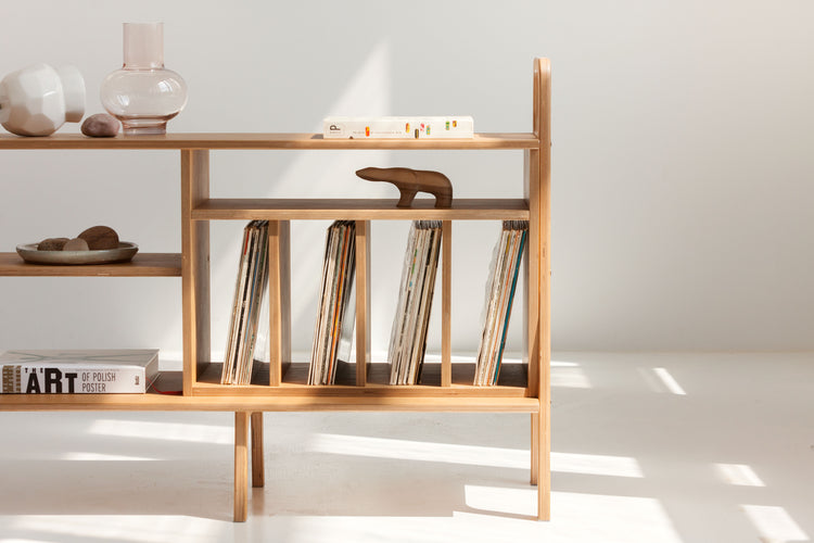 Wooden shelf with vinyls and decorative items against a white wall