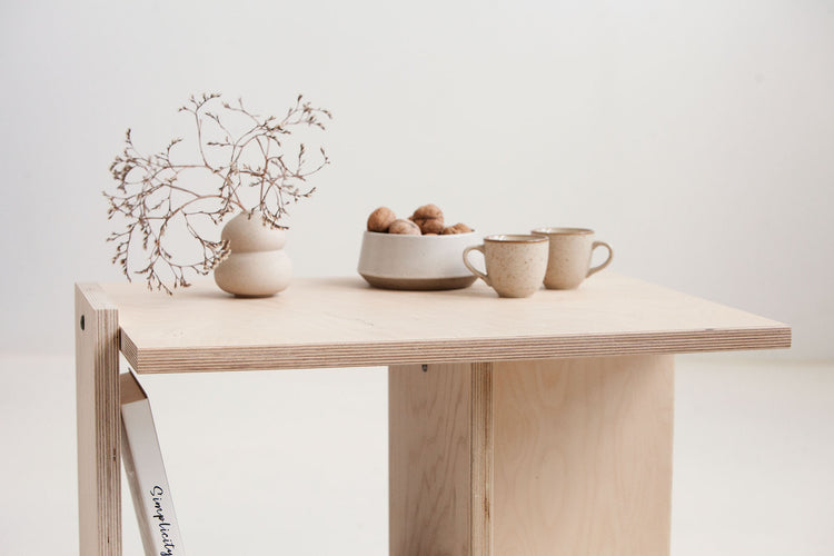 Minimalist wooden table with decorative items on a plain background