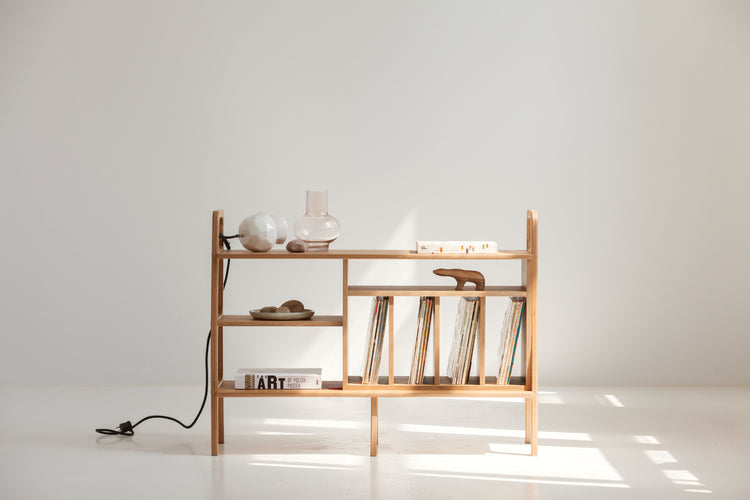 Wooden shelf with vinyls and decorative items against a white wall