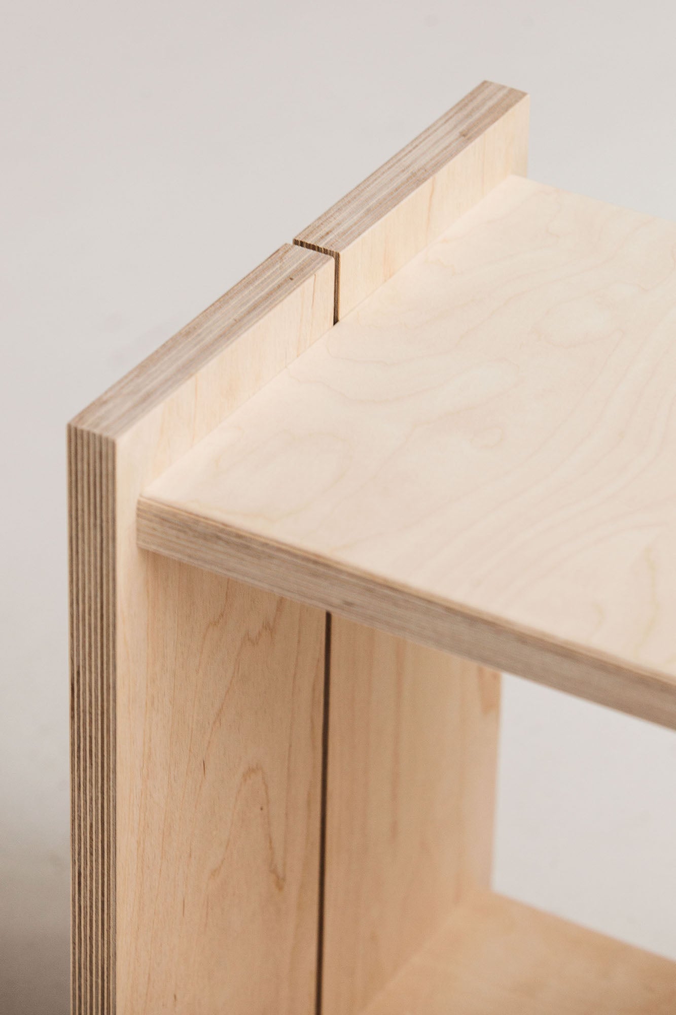 Close-up of a wooden bench corner with a light gray background