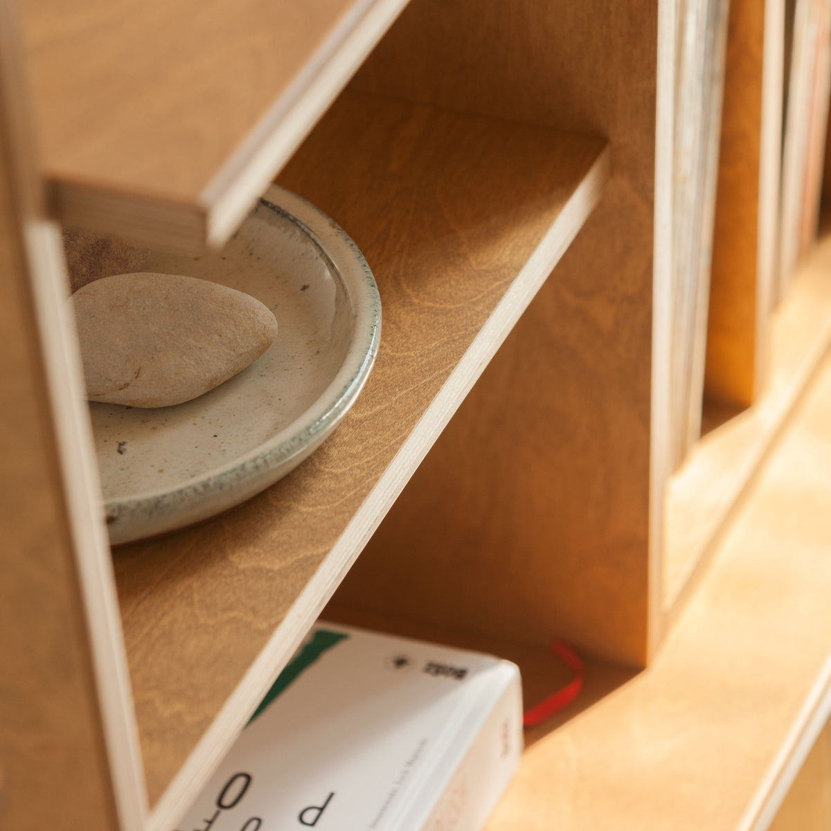 Stack of ceramic plates on a wooden shelf with a blurred background