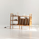 Wooden shelf with books and decorative items on a white floor and background
