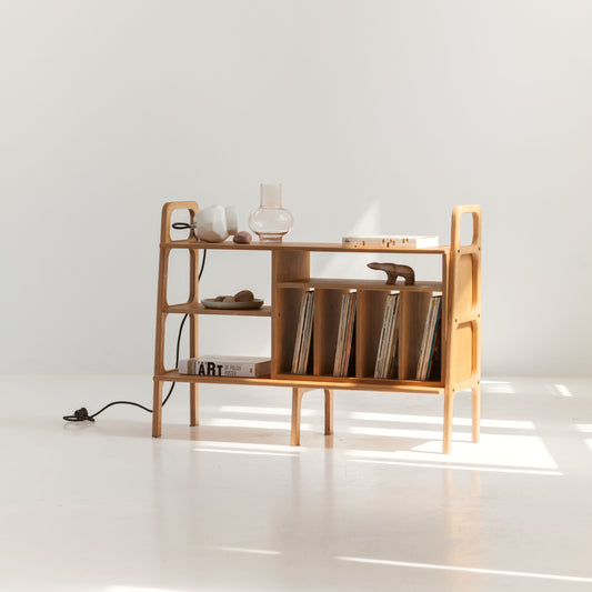 Wooden shelf with books and decorative items on a white floor and background