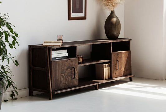 Wooden sideboard with decorative items in a room with a plant and framed picture.