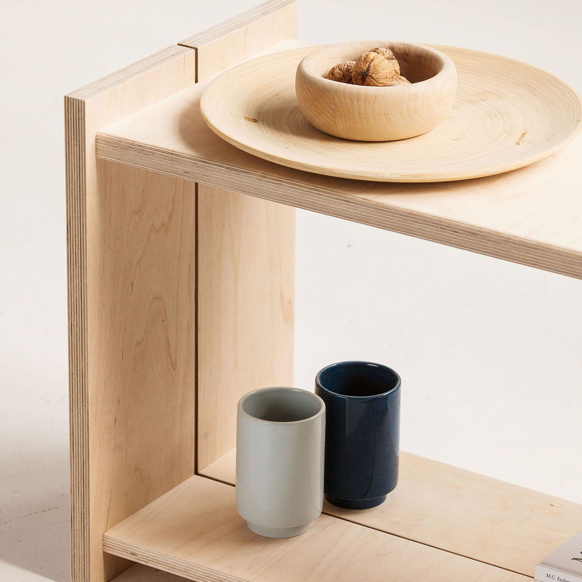 Wooden bench with ceramic bowls and cups on a light background