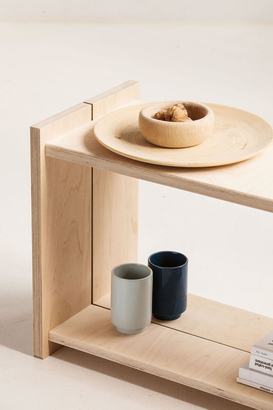 Wooden bench with ceramic bowls and cups on a light background