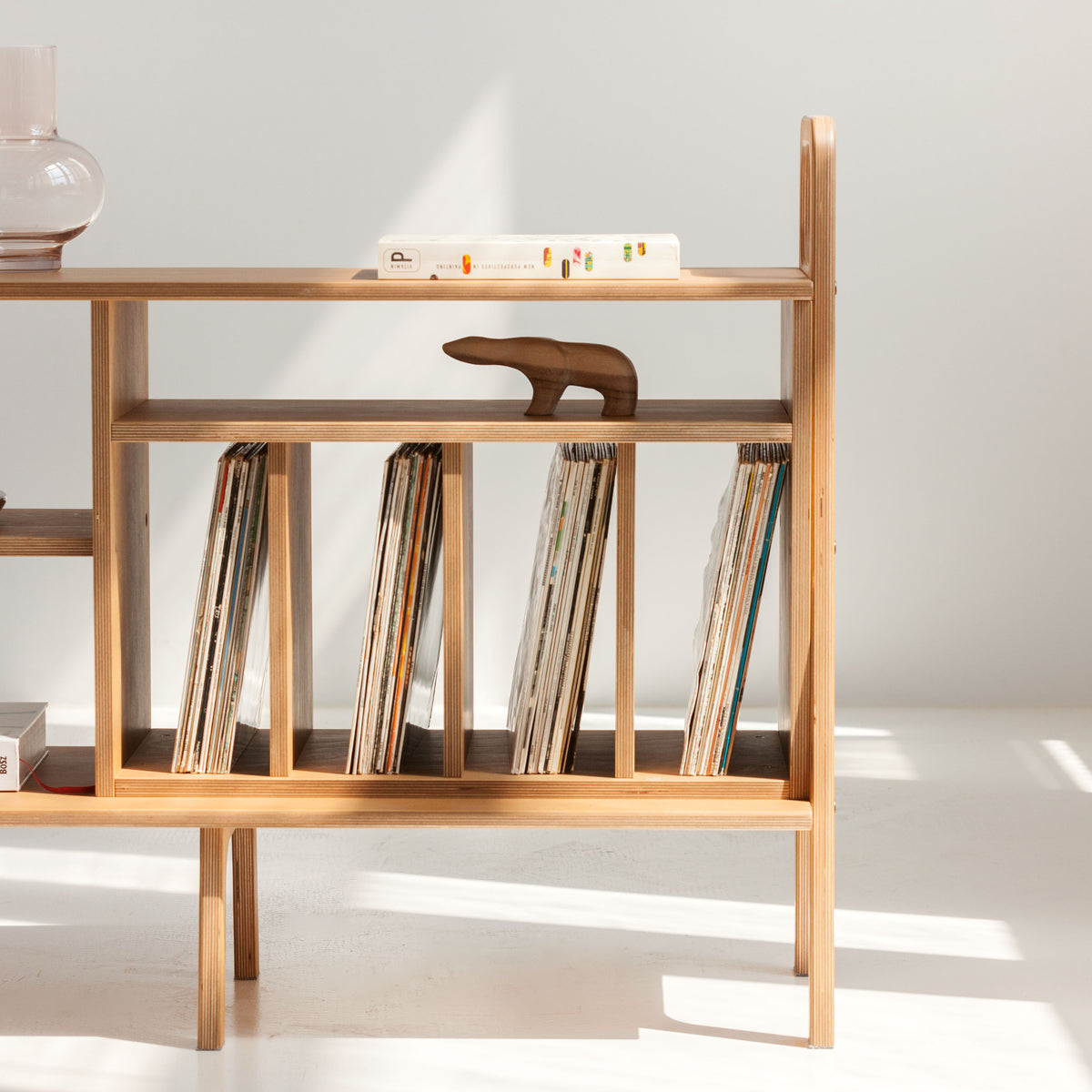 Wooden shelf with vinyls and decorative items against a white wall