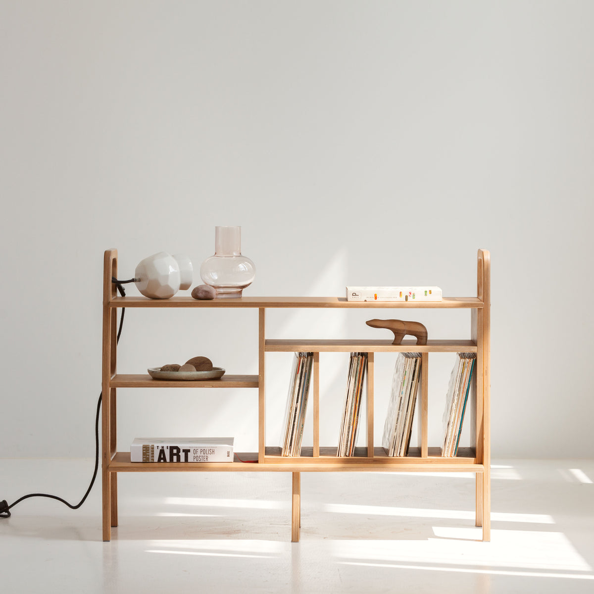 Wooden shelf with vinyls and decorative items against a white wall